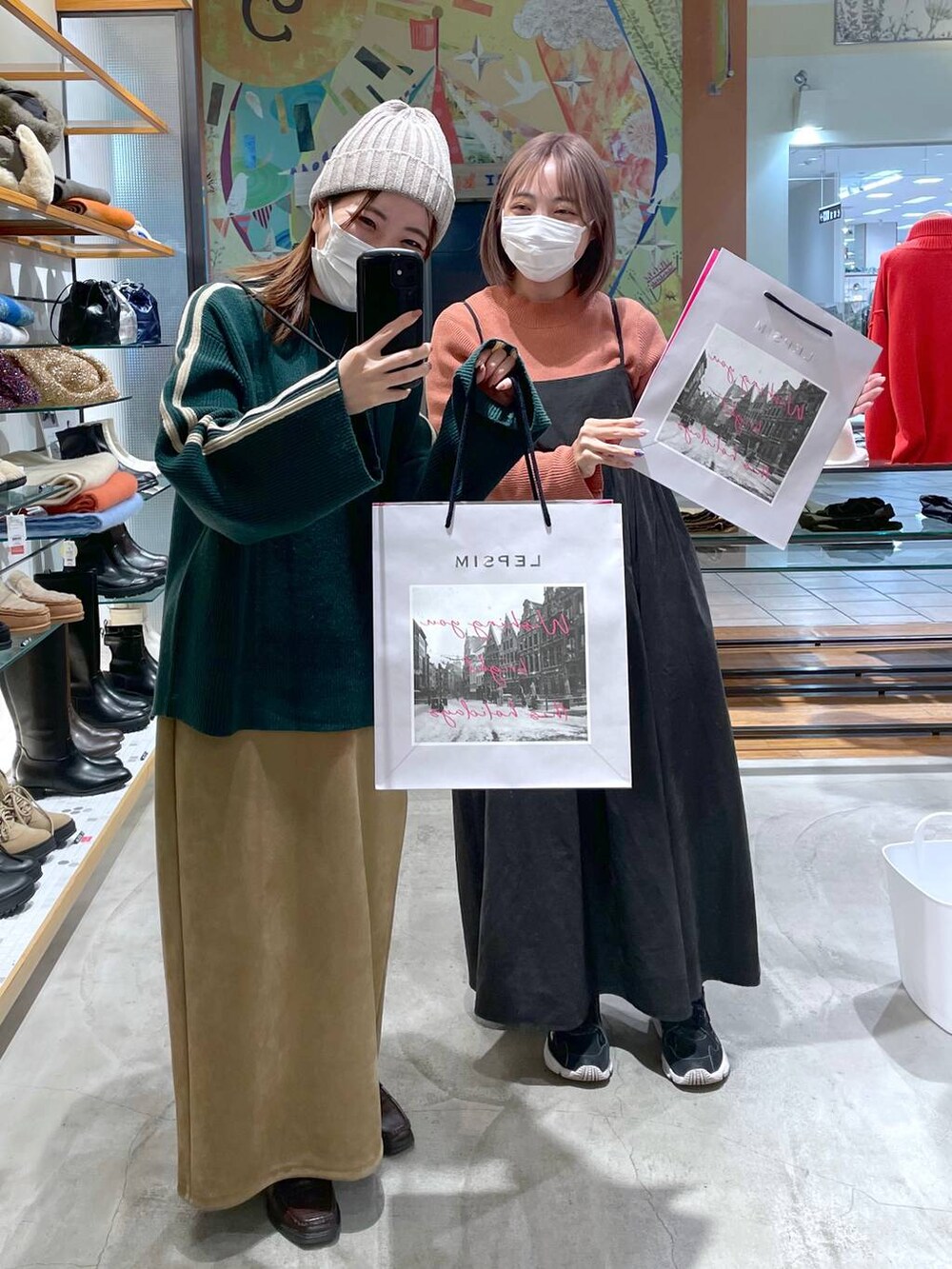 オレンジ系のニット/セーター、ベージュ系のスカート、グレー系のワンピースを着用したレディースの冬コーディネートの2枚目の写真