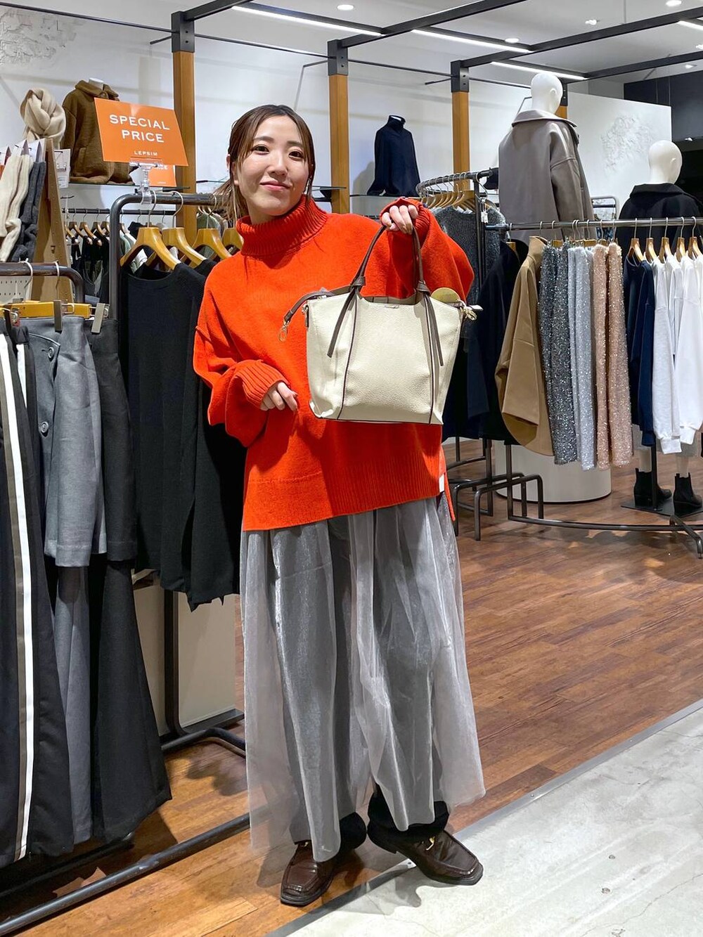 レッド系のニット/セーター、ベージュ系のショルダーバッグ、ブラック系のその他パンツを着用したレディースの冬コーディネートの2枚目の写真