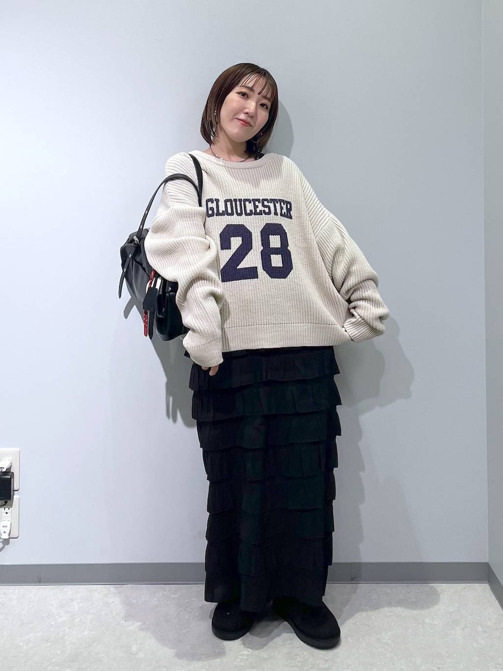 ブラック系のスカート、ブラック系のブーツ、ブラック系のボストンバッグを着用したレディースの冬コーディネートの4枚目の写真