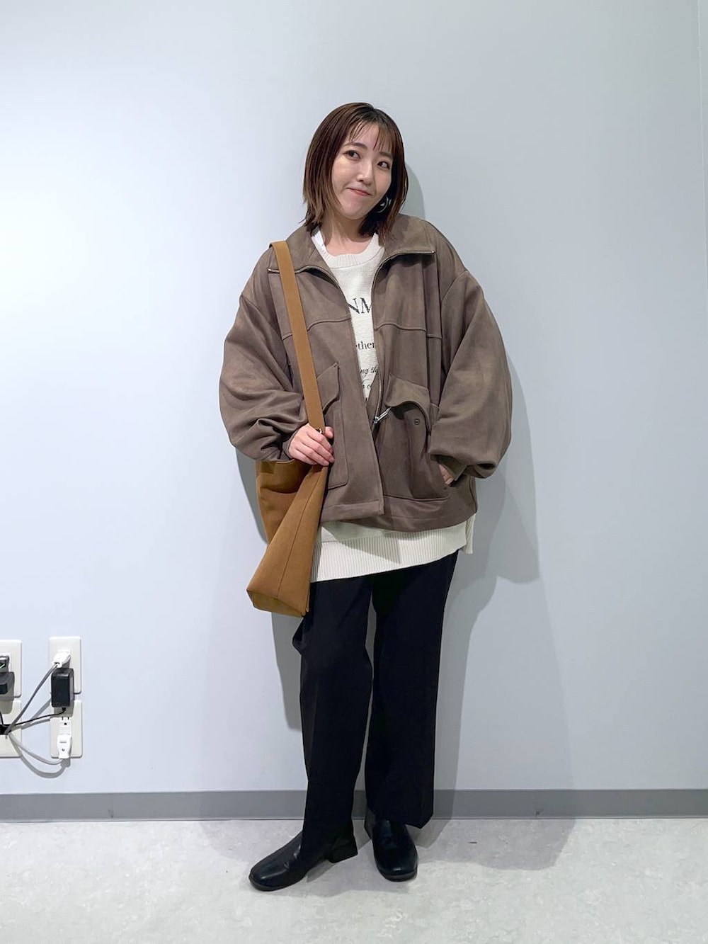 ブラック系のスラックス、ベージュ系のショルダーバッグ、ブラウン系のブルゾンを着用したレディースの秋コーディネートの3枚目の写真