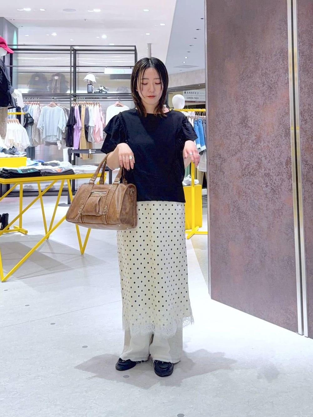 ホワイト系のデニムパンツ、ブラウン系のボストンバッグ、ブラック系のTシャツ/カットソーを着用したレディースの春コーディネートの2枚目の写真