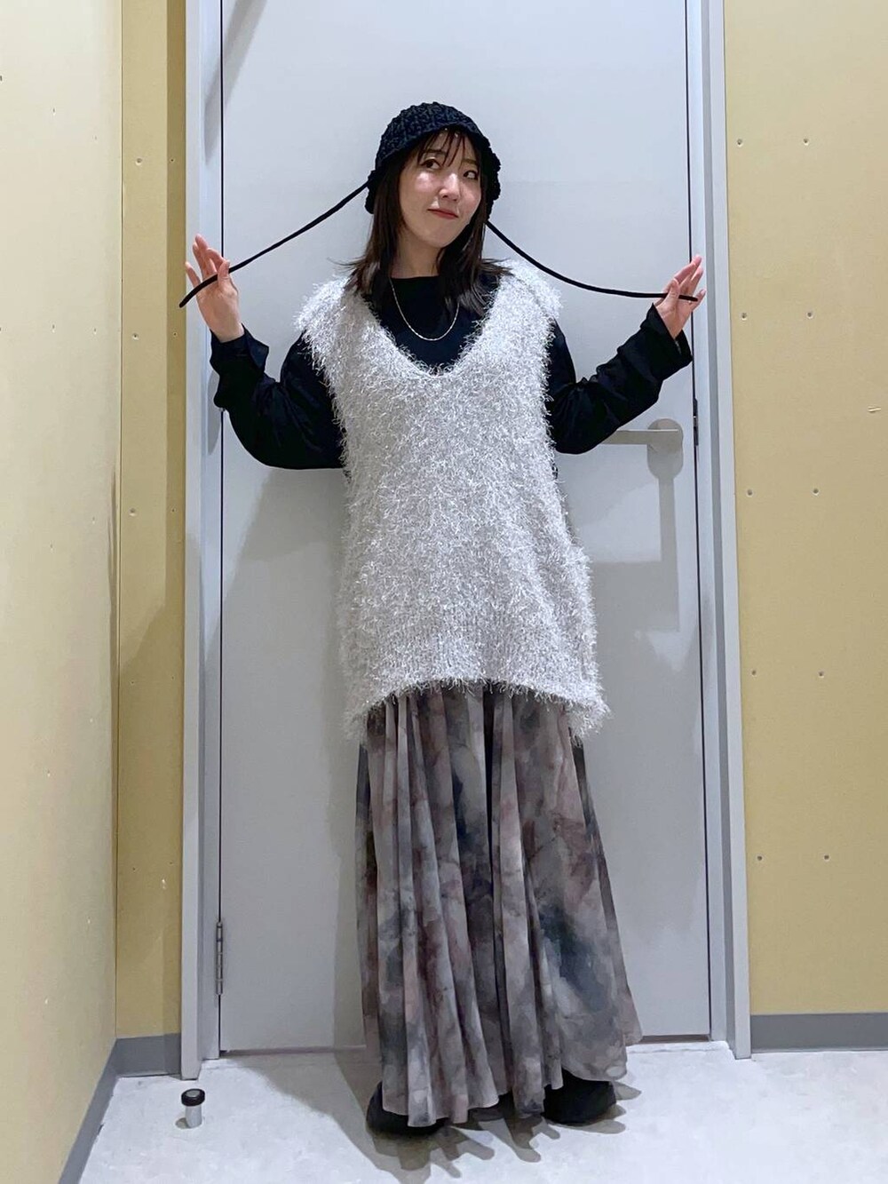 グレー系のニット/セーター、ブラック系のローファー、グレー系のスカートを着用したレディースの春コーディネートの2枚目の写真