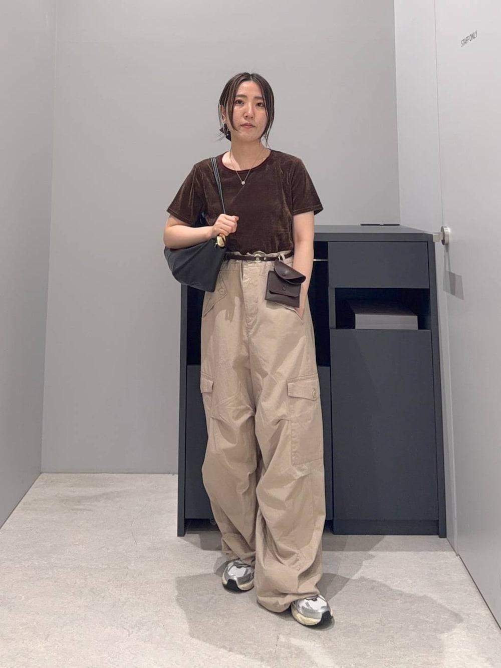 ベージュ系のカーゴパンツ、ブラウン系のTシャツ/カットソー、ブラック系のショルダーバッグを着用したレディースの夏コーディネートの3枚目の写真