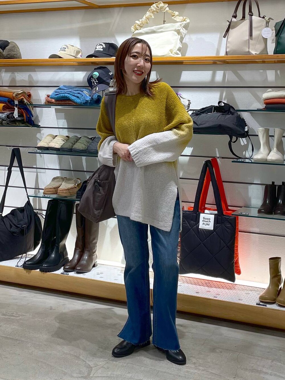 ブルー系のデニムパンツ、ブラック系のブーツ、イエロー系のニット/セーターを着用したレディースの冬コーディネートの2枚目の写真