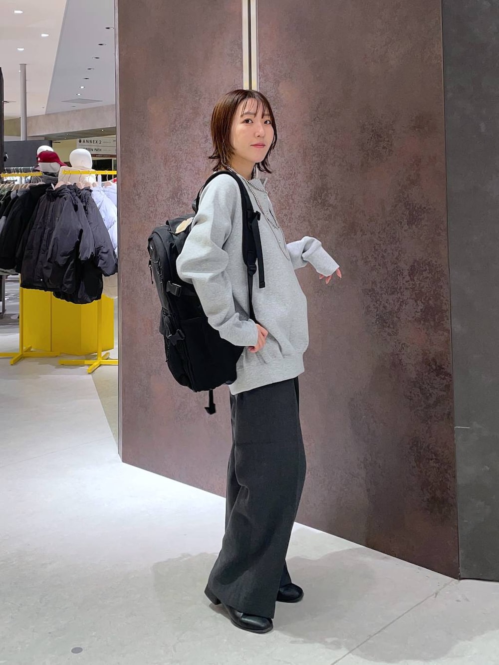 グレー系のスラックス、ブラック系のバックパック/リュック、グレー系のスウェットを着用したレディースの冬コーディネートの3枚目の写真