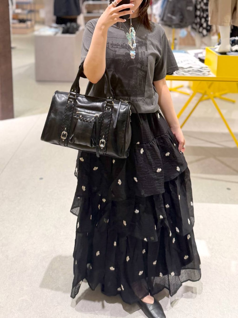 ブラック系のボストンバッグ、ブラック系のスカート、ブラック系のTシャツ/カットソーを着用したレディースの夏コーディネートの2枚目の写真