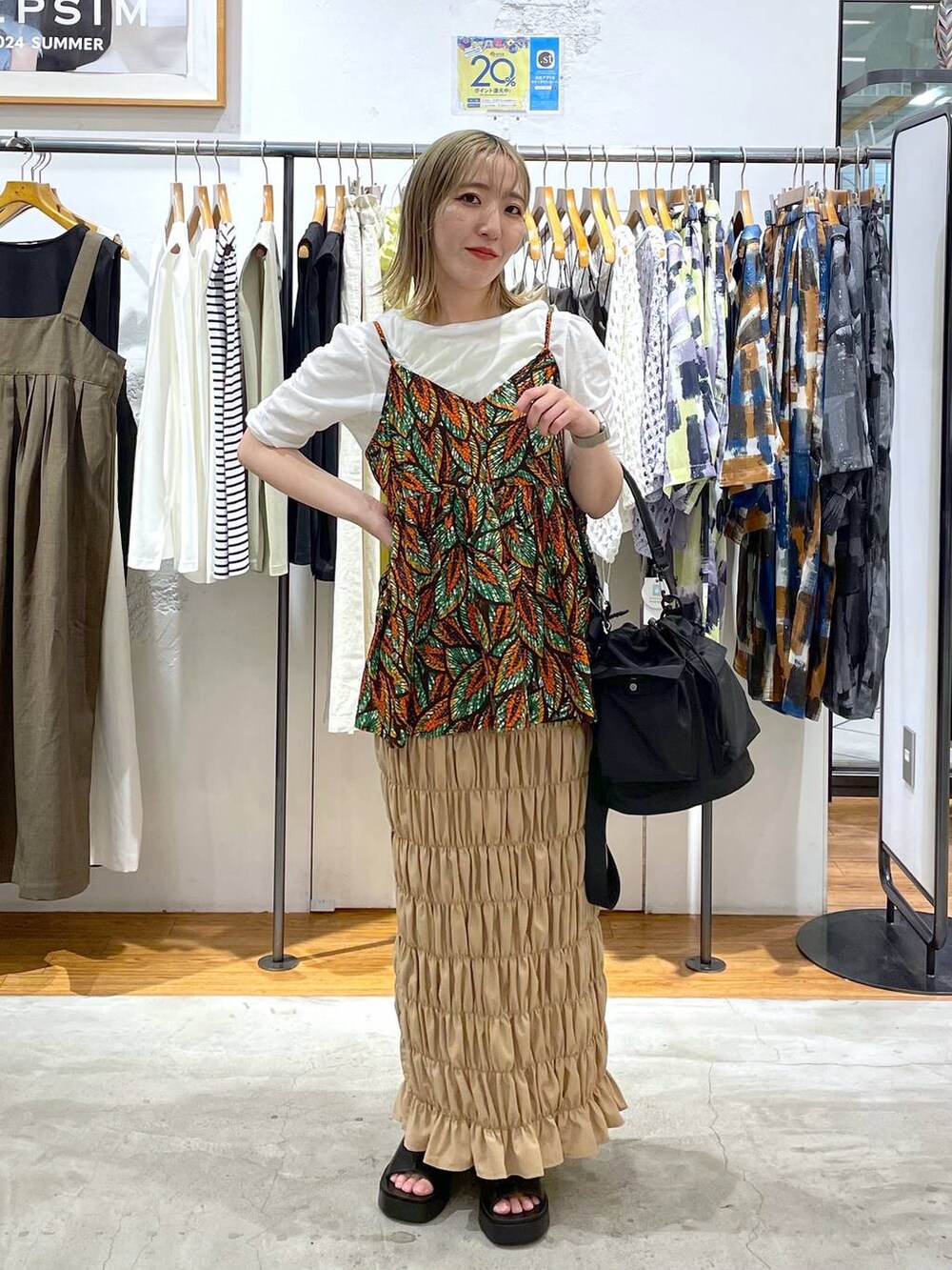 ブラック系のショルダーバッグ、ブラック系のサンダル、ベージュ系のスカートを着用したレディースの夏コーディネートの2枚目の写真