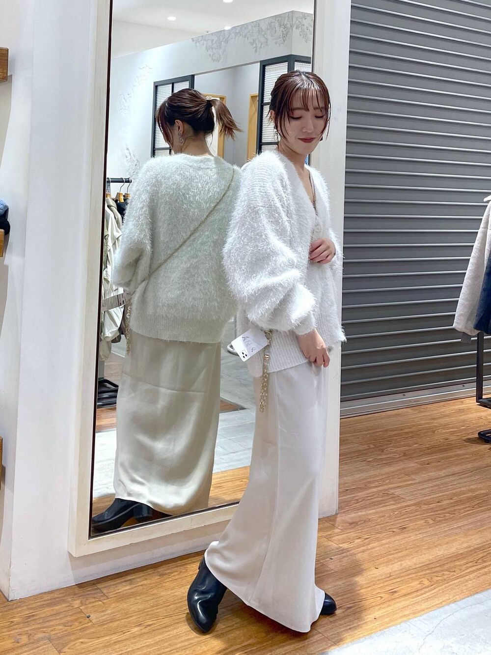 ホワイト系のスカート、ホワイト系のニット/セーター、ベージュ系のスマホグッズを着用したレディースの冬コーディネートの2枚目の写真