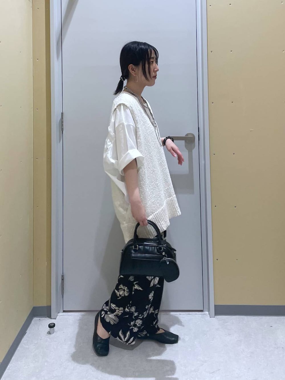 ホワイト系のニット/セーター、ホワイト系のTシャツ/カットソー、ブラック系のショルダーバッグを着用したレディースの春コーディネートの2枚目の写真