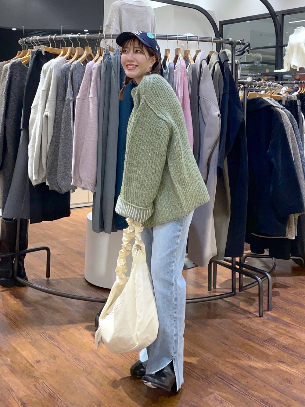 グリーン系のニット/セーター、ホワイト系のショルダーバッグ、ブルー系のデニムパンツを着用したレディースの秋コーディネートの3枚目の写真