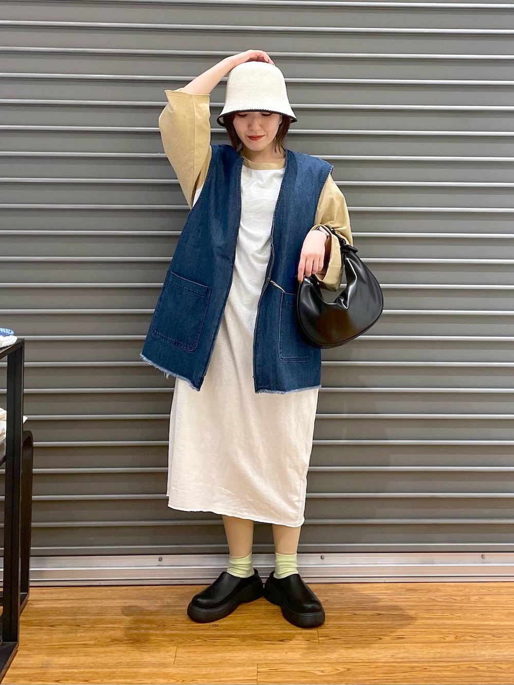 ベージュ系のワンピース、ブラック系のショルダーバッグ、ブルー系のベストを着用したレディースの春コーディネートの3枚目の写真