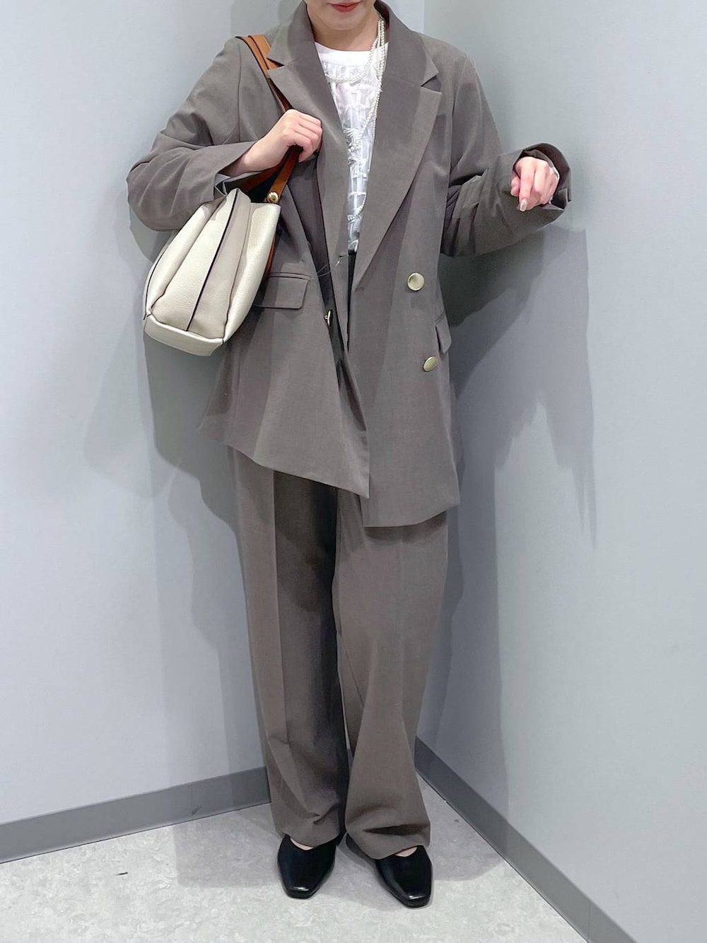 ブラック系のパンプス、ブラウン系のスラックス、ホワイト系のシャツ/ブラウスを着用したレディースの冬コーディネートの2枚目の写真