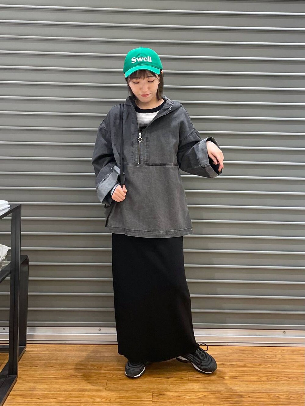 ブラック系のショルダーバッグ、ホワイト系のTシャツ/カットソー、ブラック系のスカートを着用したレディースの春コーディネートの2枚目の写真