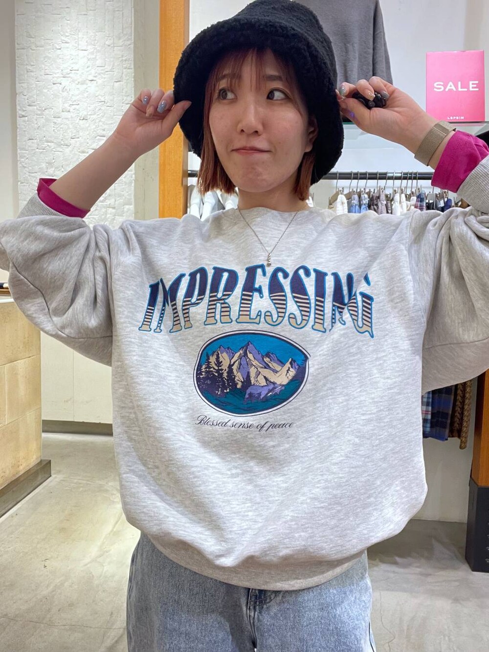 グレー系のスウェット、ブルー系のデニムパンツ、レッド系のTシャツ/カットソーを着用したレディースの冬コーディネートの2枚目の写真