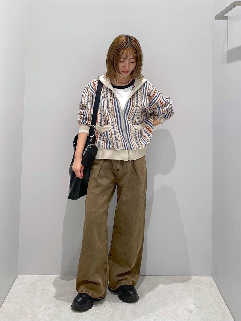 ブラック系のショルダーバッグ、ブラウン系のデニムパンツ、ベージュ系のカーディガン/ボレロを着用したレディースの秋コーディネートの3枚目の写真