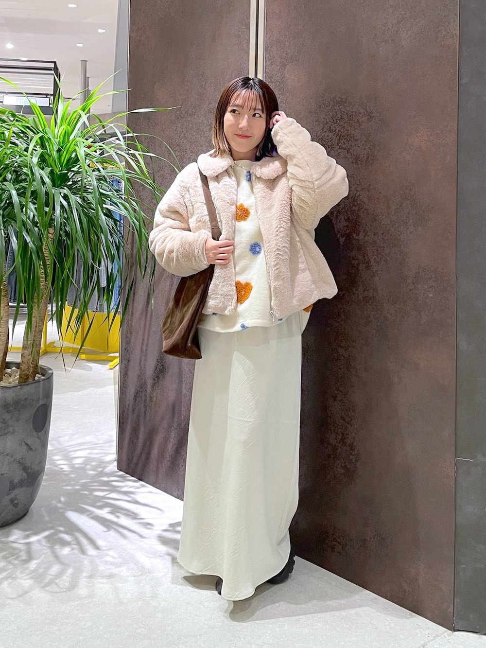 ブラウン系のショルダーバッグ、ホワイト系のスカート、ホワイト系のブルゾンを着用したレディースの冬コーディネートの2枚目の写真