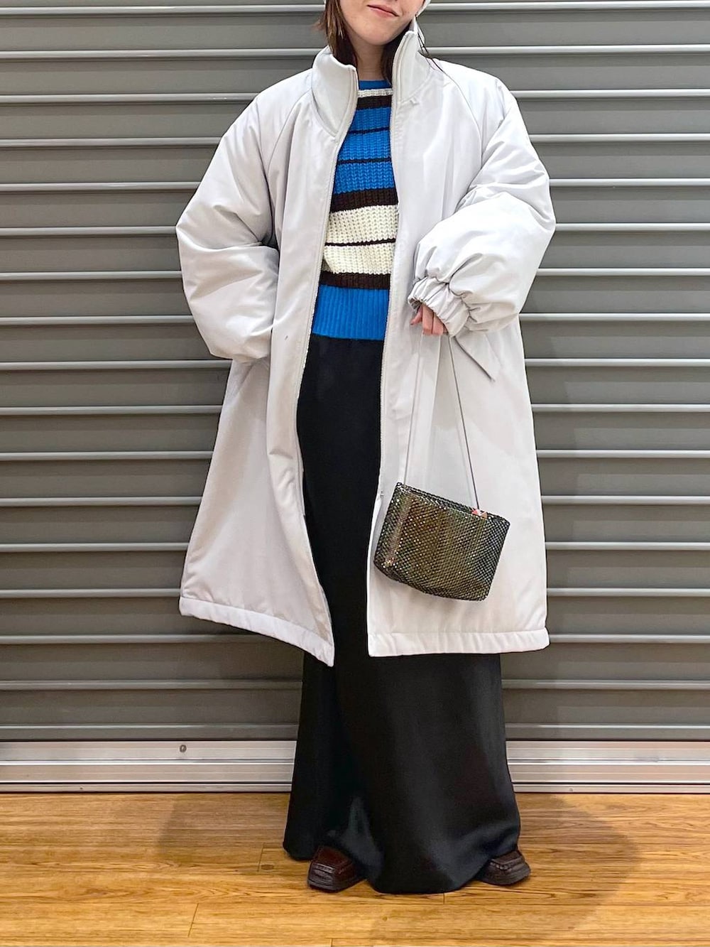 ブラック系のスカート、ブラック系のショルダーバッグ、ブルー系のニット/セーターを着用したレディースの冬コーディネートの2枚目の写真