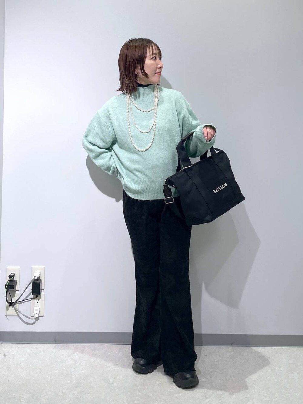 グリーン系のニット/セーター、ブラック系のその他パンツ、ブラック系のトートバッグを着用したレディースの冬コーディネートの2枚目の写真