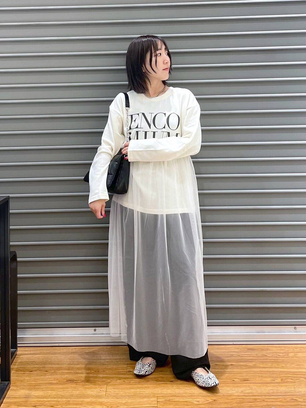 ブラック系のショルダーバッグ、グレー系のチノパンツ、ホワイト系のパンプスを着用したレディースの秋コーディネートの2枚目の写真