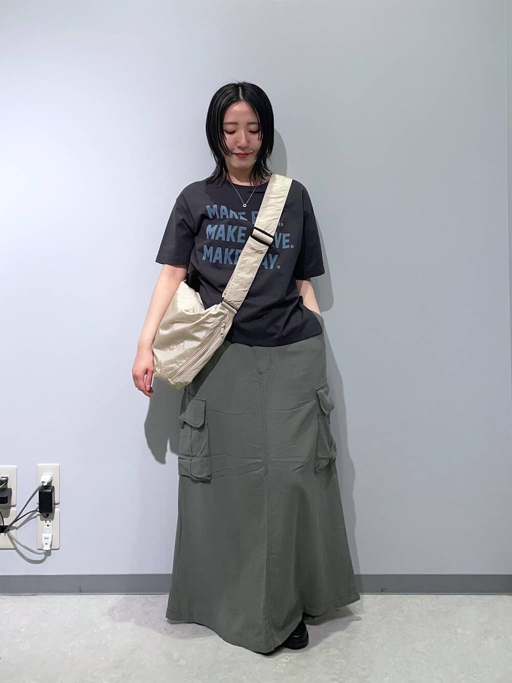 グリーン系のスカート、グレー系のTシャツ/カットソー、ホワイト系のショルダーバッグを着用したレディースの春コーディネートの2枚目の写真