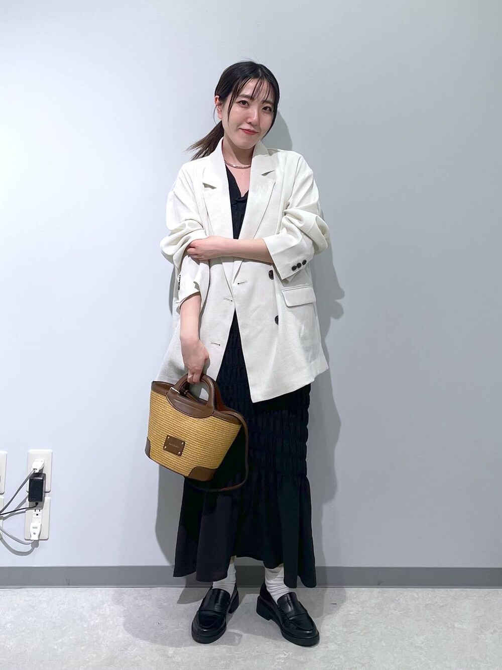 ホワイト系のテーラードジャケット、ブラウン系のショルダーバッグ、ブラック系のワンピースを着用したレディースの春コーディネートの3枚目の写真