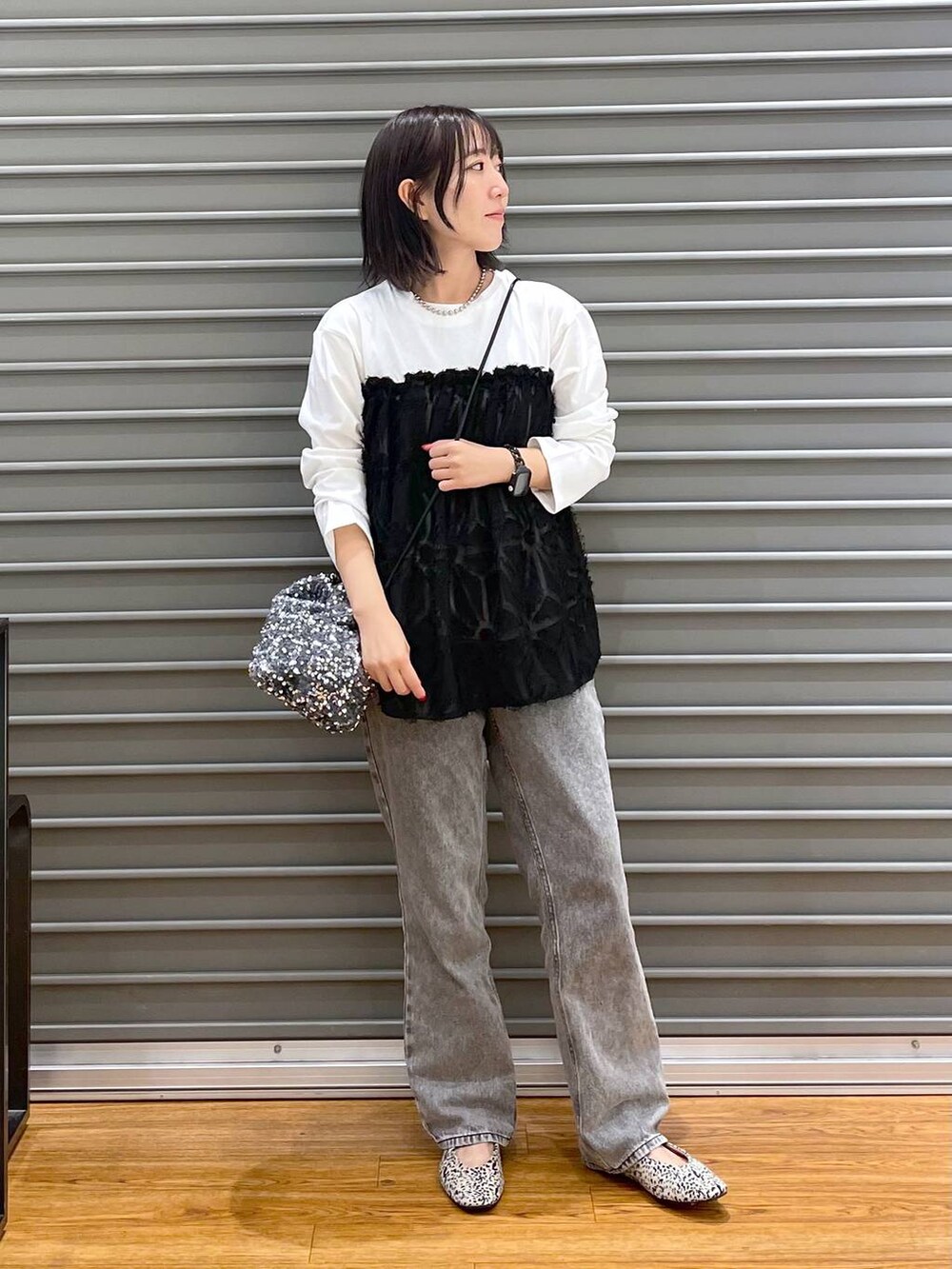 シルバー系のショルダーバッグ、ホワイト系のパンプス、グレー系のデニムパンツを着用したレディースの秋コーディネートの3枚目の写真