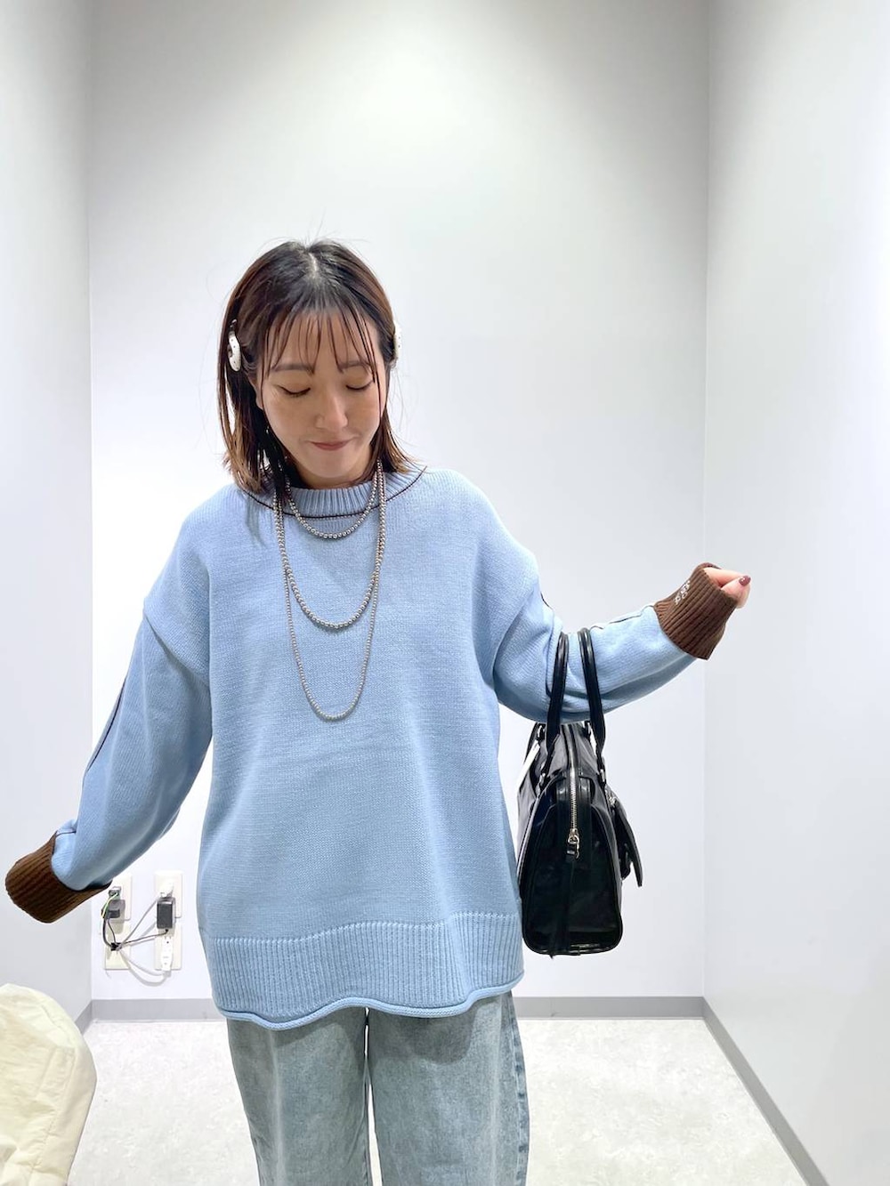 ブラック系のボストンバッグ、ブルー系のデニムパンツ、ブルー系のニット/セーターを着用したレディースの冬コーディネートの3枚目の写真