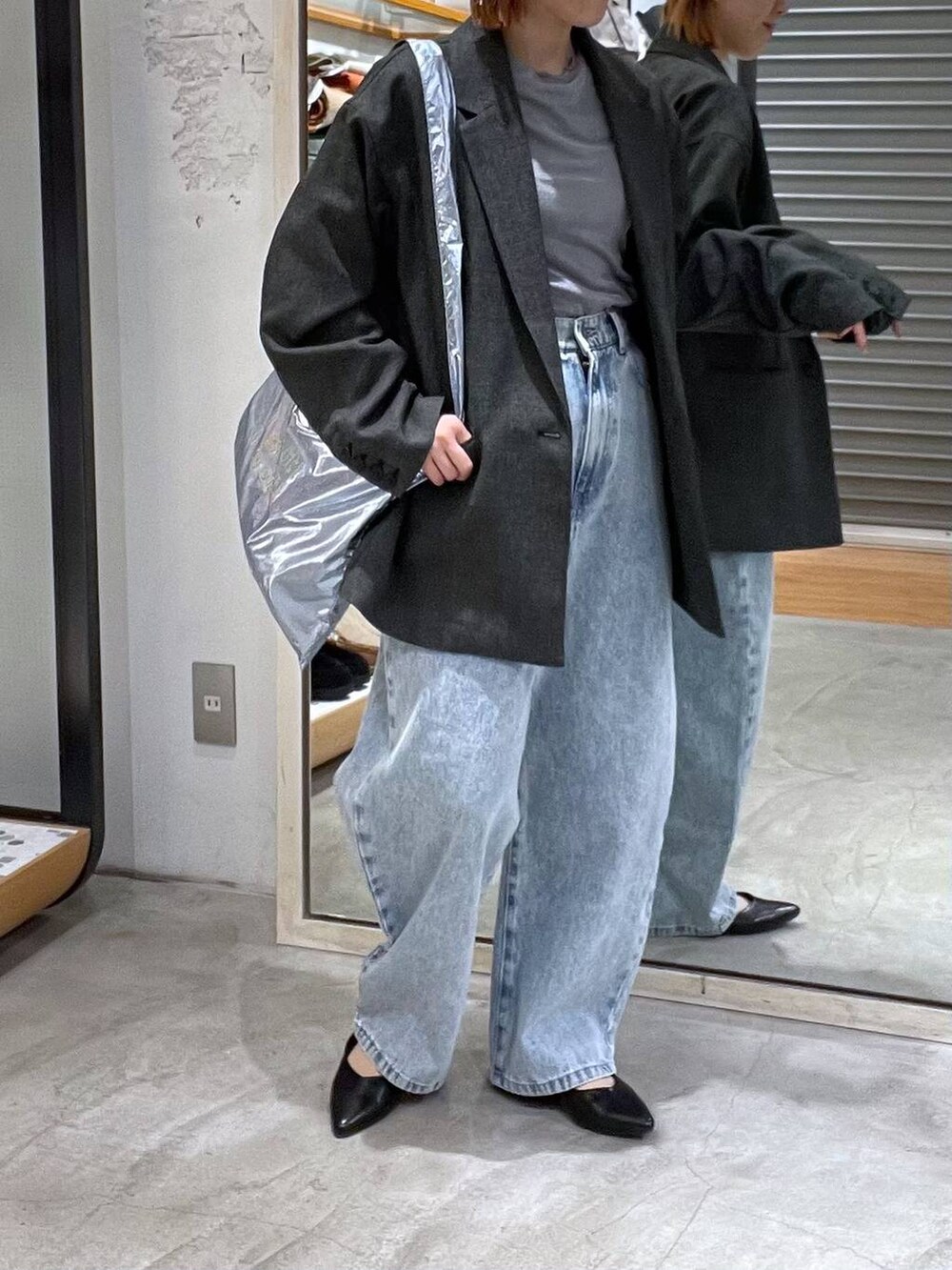 ブルー系のデニムパンツ、ブラック系のテーラードジャケット、シルバー系のトートバッグを着用したレディースの春コーディネートの3枚目の写真