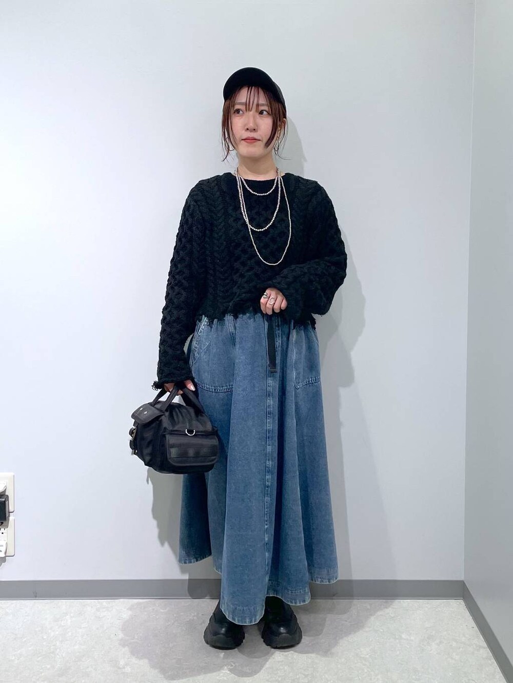 ブラック系のスカート、ブラック系のボストンバッグ、ブラック系のキャップを着用したレディースの冬コーディネートの4枚目の写真