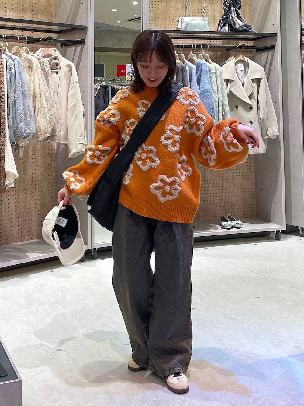 ブラック系のショルダーバッグ、ブラック系のデニムパンツ、オレンジ系のニット/セーターを着用したレディースの冬コーディネートの6枚目の写真