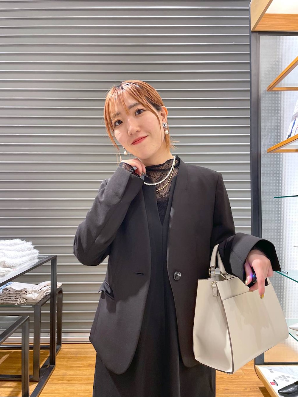 ブラック系のノーカラージャケット、ホワイト系のショルダーバッグ、グレー系のパンプスを着用したレディースの冬コーディネートの2枚目の写真