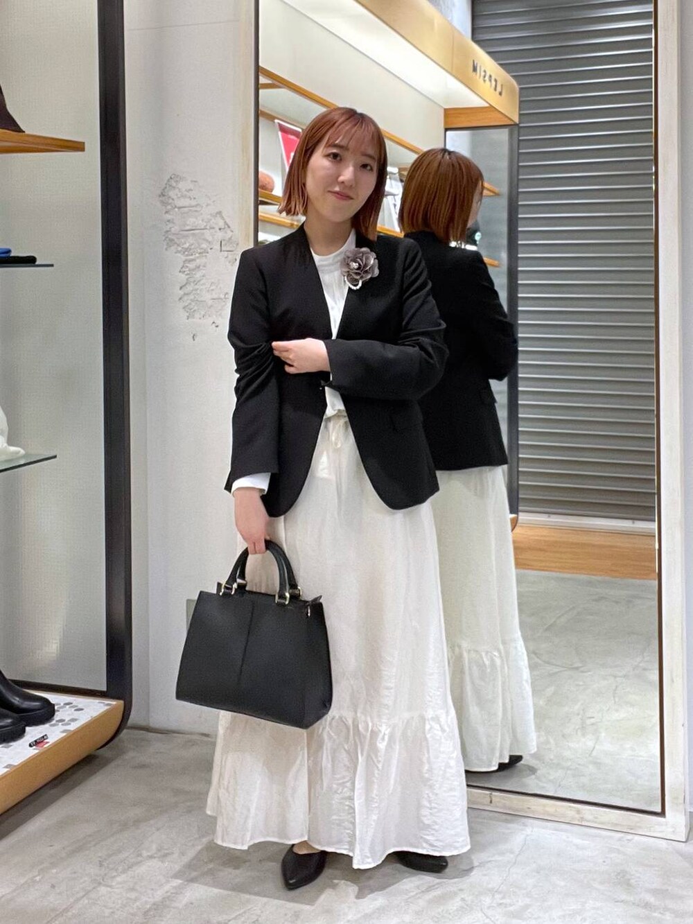 ホワイト系のスカート、ブラック系のノーカラージャケット、ホワイト系のシャツ/ブラウスを着用したレディースの冬コーディネートの4枚目の写真