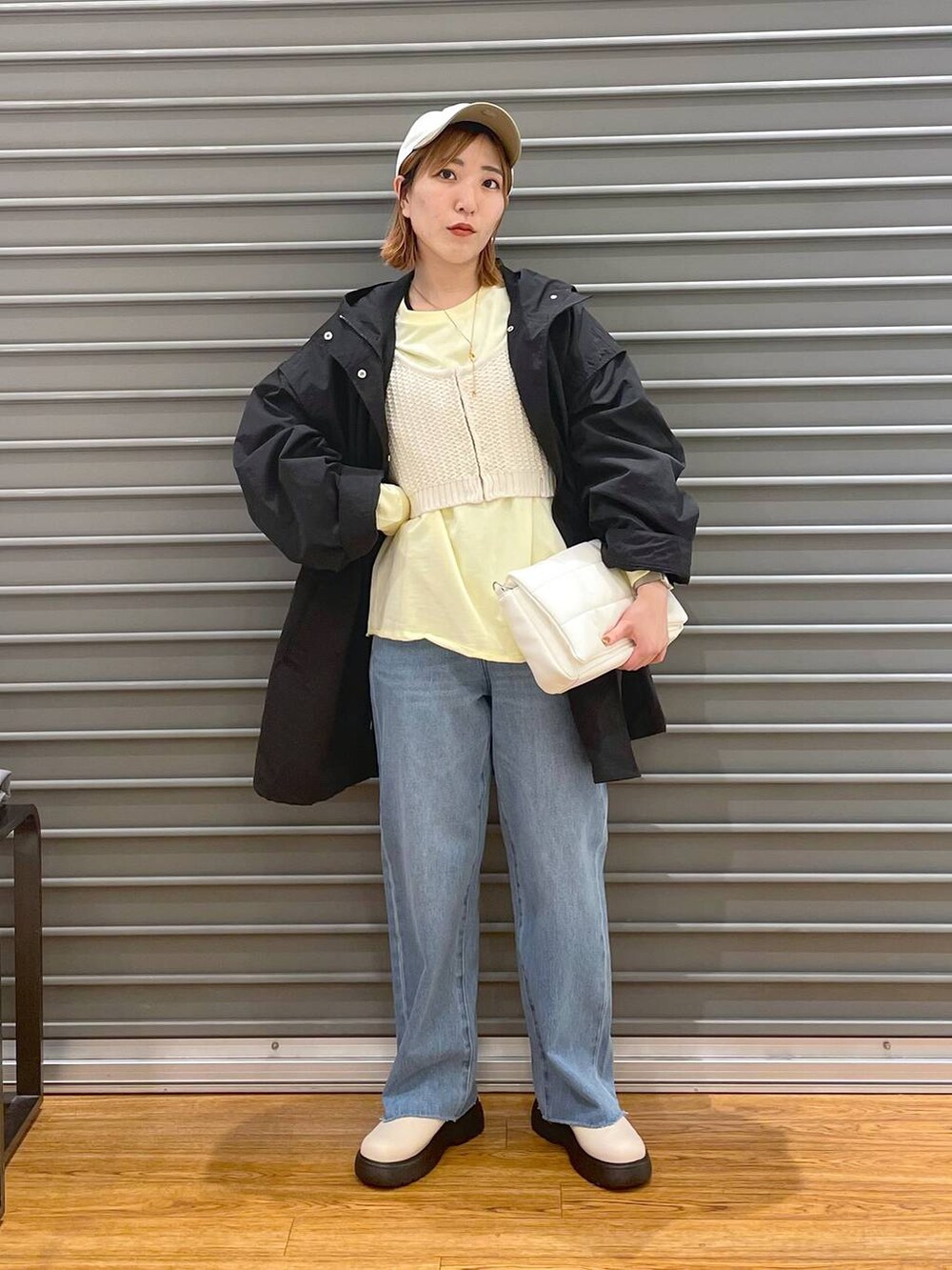 ホワイト系のショルダーバッグ、ホワイト系のニット/セーター、ブルー系のデニムパンツを着用したレディースの春コーディネートの2枚目の写真