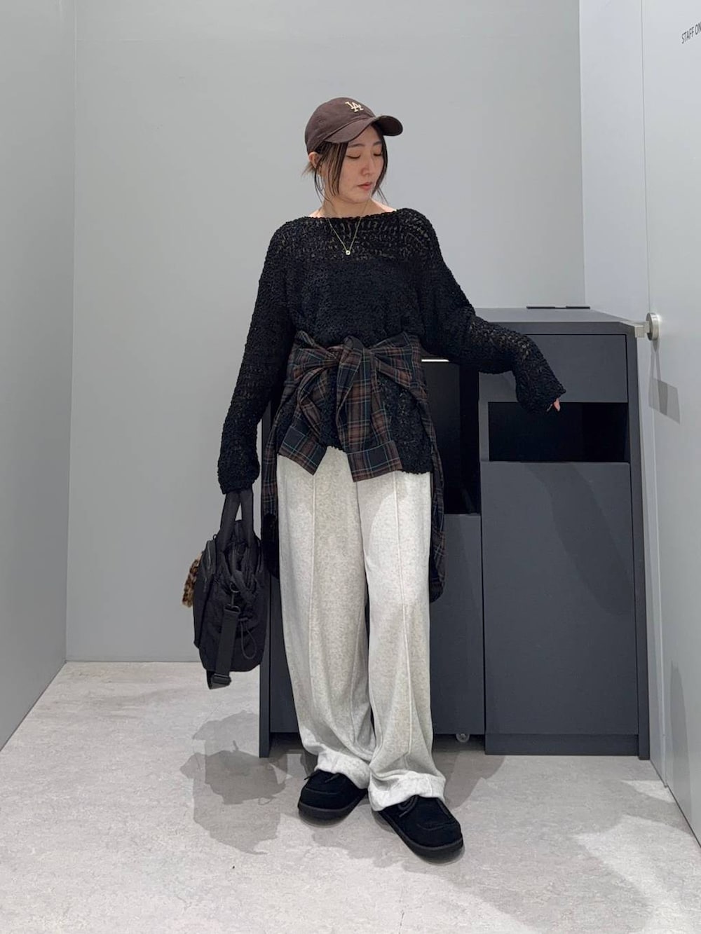 ブラック系のニット/セーター、ブラック系のトートバッグ、ブラック系のモカシン/デッキシューズを着用したレディースの秋コーディネートの3枚目の写真