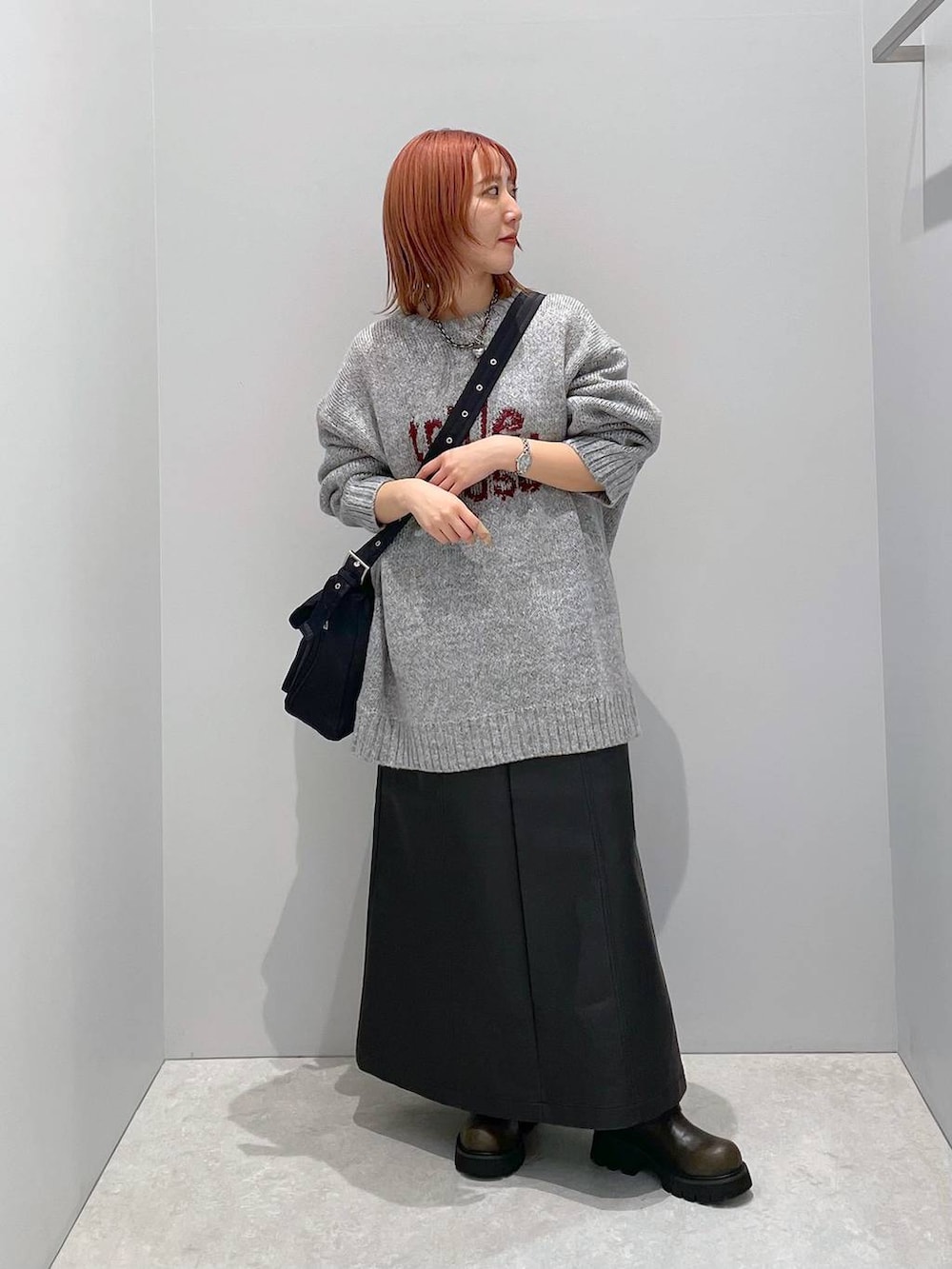 ブラック系のショルダーバッグ、グリーン系のブーツ、グレー系のニット/セーターを着用したレディースの冬コーディネートの2枚目の写真