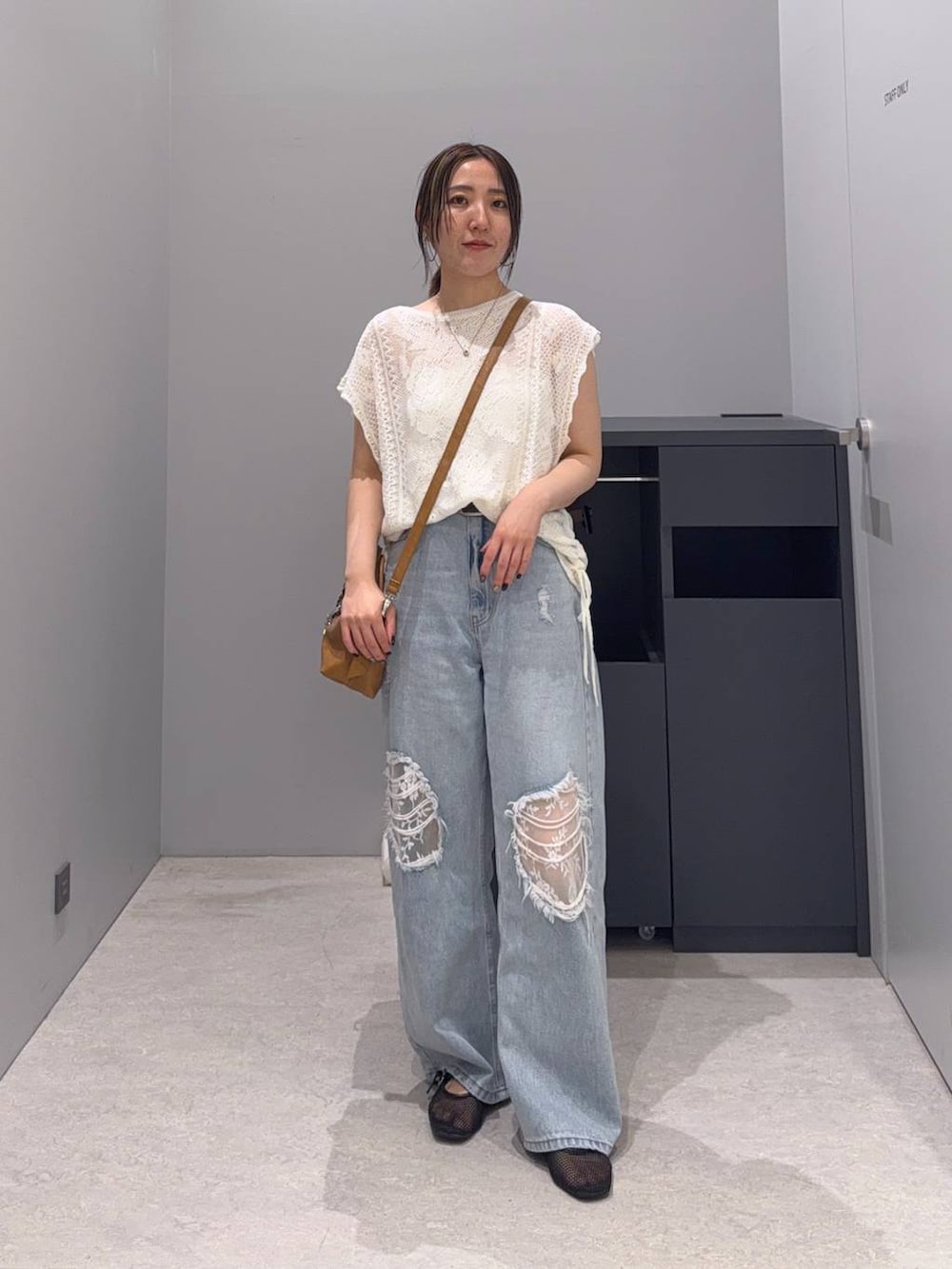 ブルー系のデニムパンツ、ブラウン系のボストンバッグ、ホワイト系のニット/セーターを着用したレディースの夏コーディネートの2枚目の写真