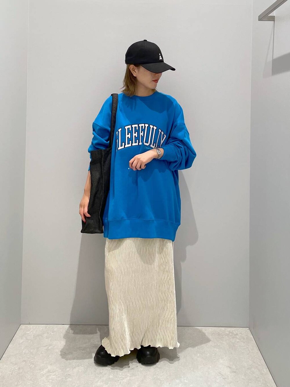 ブラック系のトートバッグ、ブルー系のスウェット、ホワイト系のスカートを着用したレディースの秋コーディネートの2枚目の写真