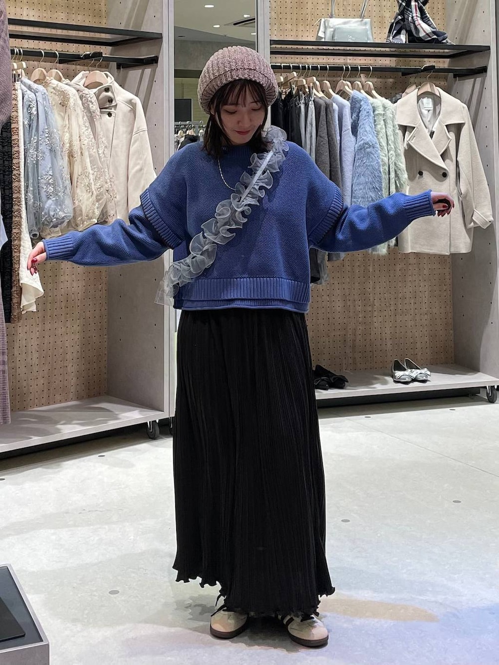 ベージュ系のワンピース、ブルー系のニット/セーター、グレー系のスマホグッズを着用したレディースの冬コーディネートの4枚目の写真