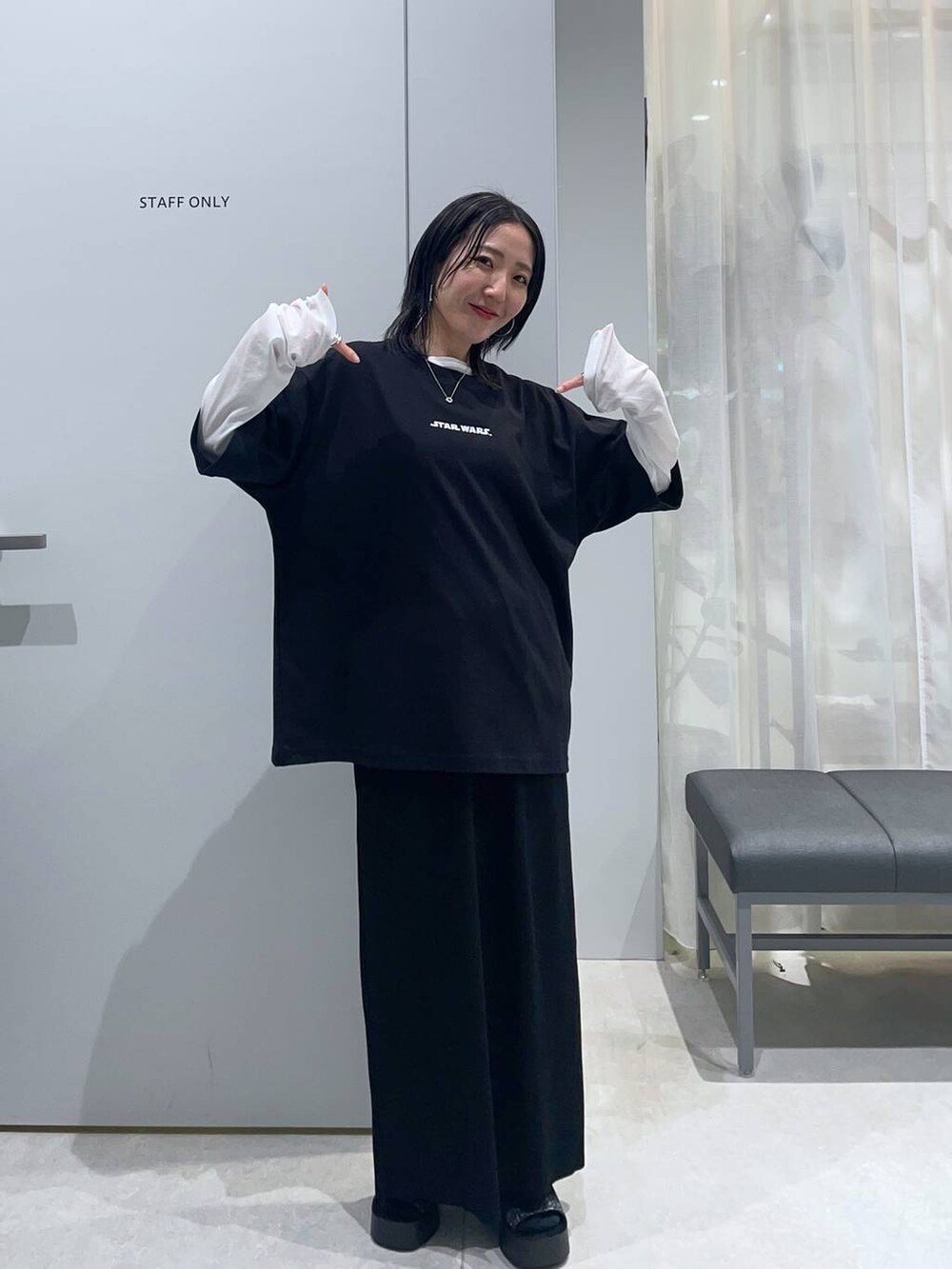 ブラック系のスカート、ホワイト系のTシャツ/カットソー、ブラック系のサンダルを着用したレディースの春コーディネートの2枚目の写真