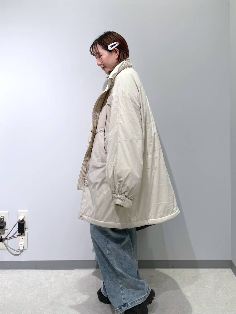 ホワイト系のブルゾン、ブラック系のボストンバッグ、ブルー系のデニムパンツを着用したレディースの冬コーディネートの2枚目の写真