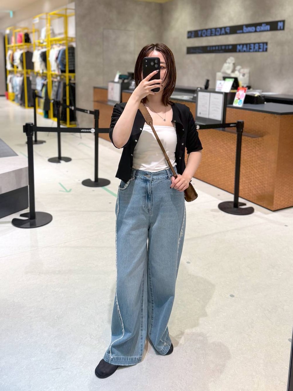 ブルー系のデニムパンツ、ブラック系のTシャツ/カットソー、ブラウン系のショルダーバッグを着用したレディースの夏コーディネートの2枚目の写真