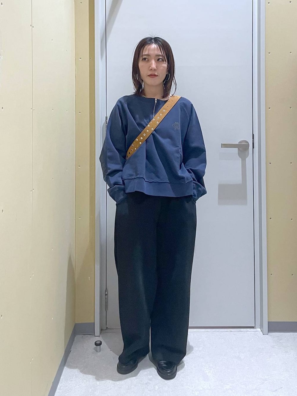 ブラウン系のボストンバッグ、ブラック系のスウェットパンツ、ブルー系のスウェットを着用したレディースの春コーディネートの2枚目の写真