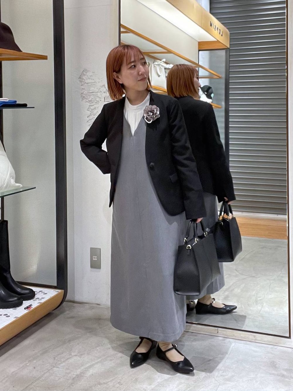 ブラック系のノーカラージャケット、ホワイト系のシャツ/ブラウス、ブラック系のショルダーバッグを着用したレディースの冬コーディネートの3枚目の写真