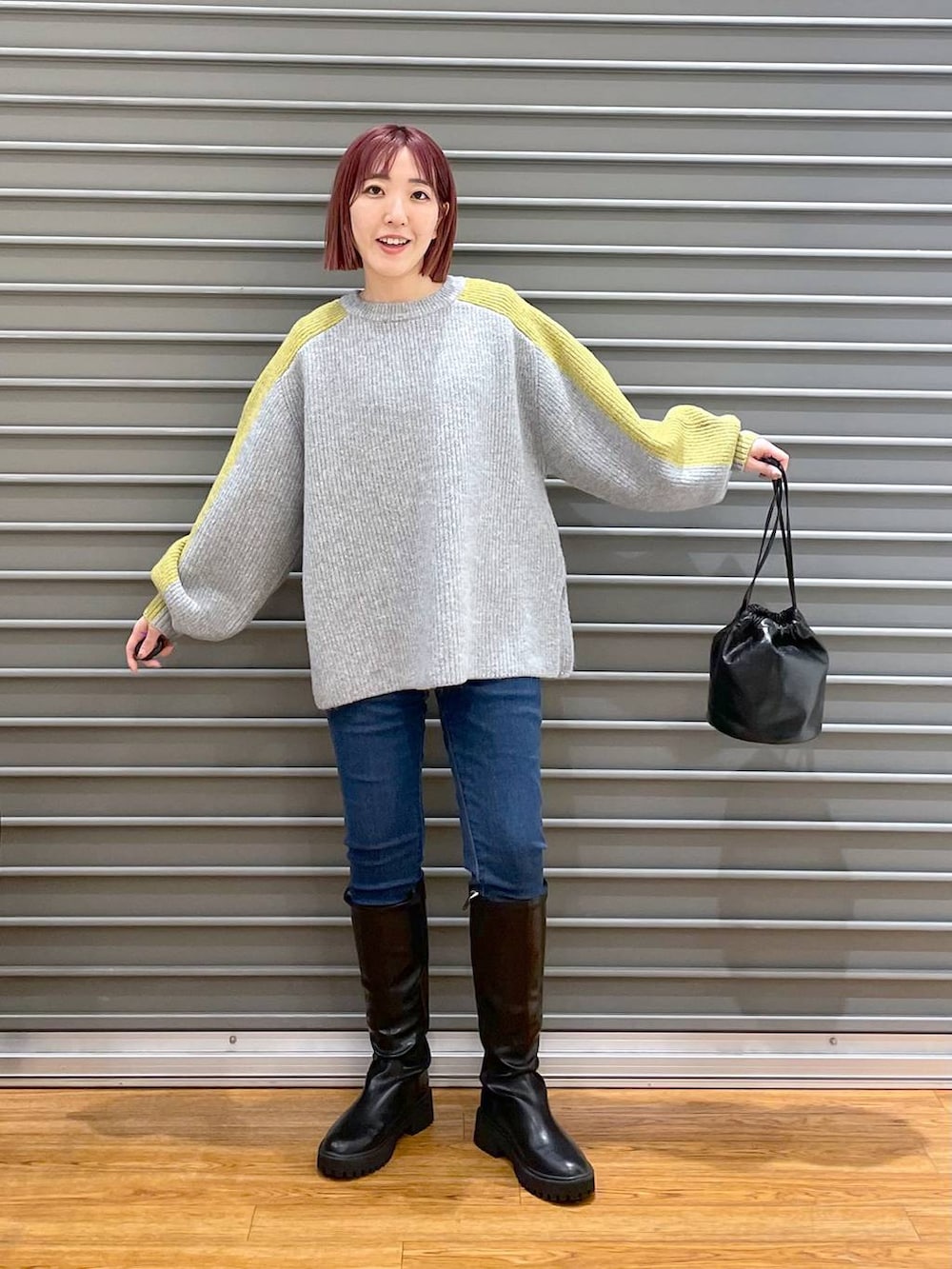 ブラック系のブーツ、グレー系のニット/セーター、シルバー系のショルダーバッグを着用したレディースの冬コーディネートの2枚目の写真