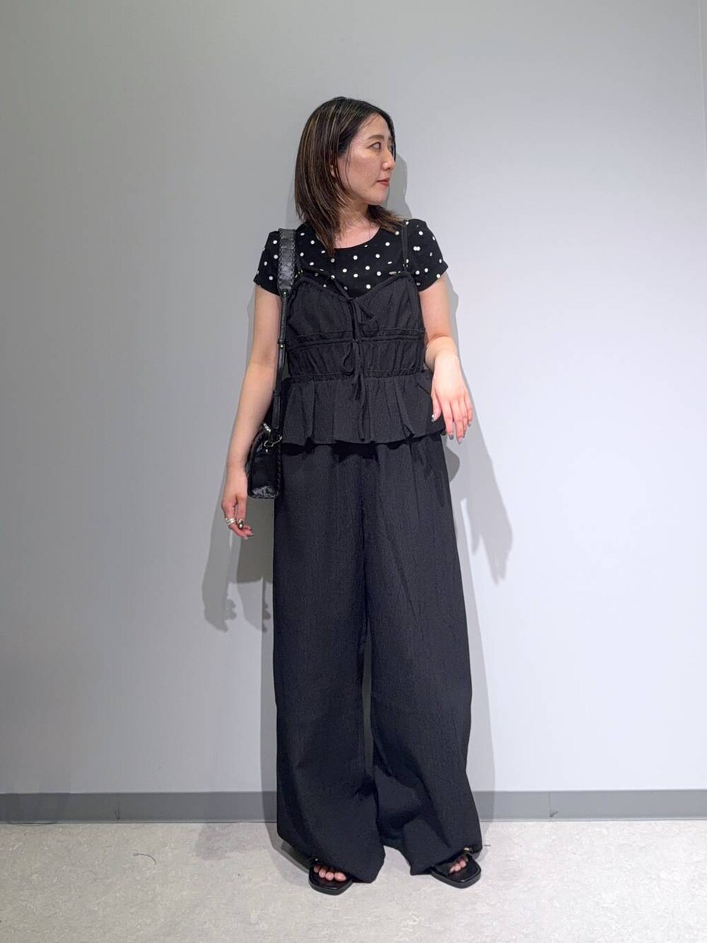ブラック系のサロペット/オーバーオール、ブラック系のサンダル、ブラック系のショルダーバッグを着用したレディースの夏コーディネートの2枚目の写真