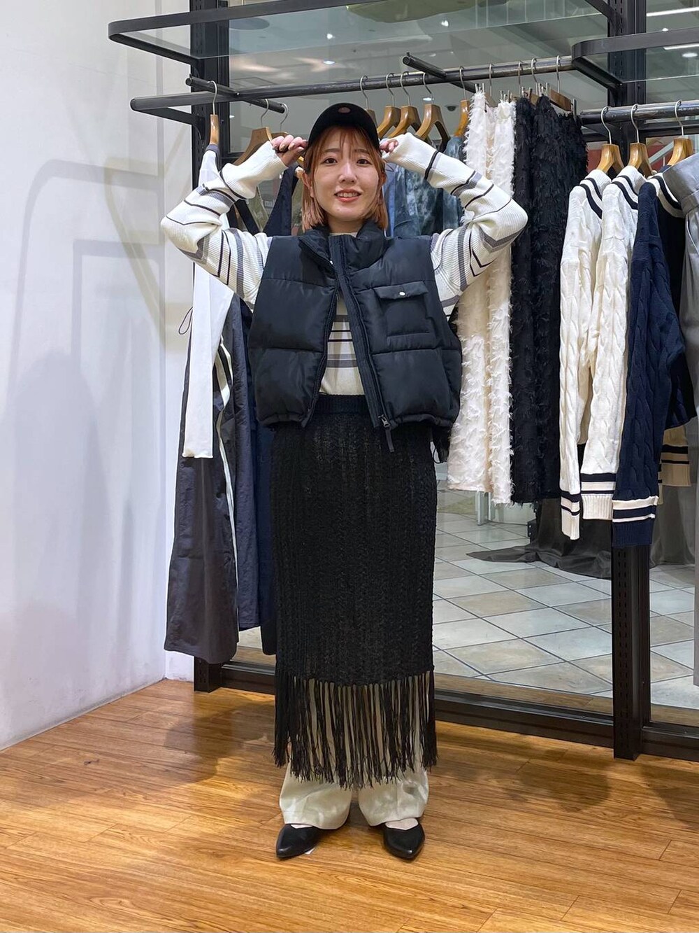 ブラック系のベスト、グリーン系のスラックス、ホワイト系のニット/セーターを着用したレディースの春コーディネートの2枚目の写真