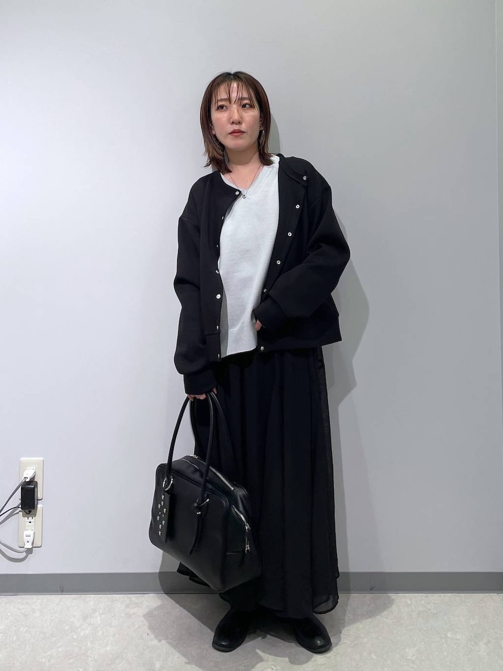 グレー系のニット/セーター、ブラック系のカーディガン/ボレロ、ブラック系のボストンバッグを着用したレディースの春コーディネートの2枚目の写真