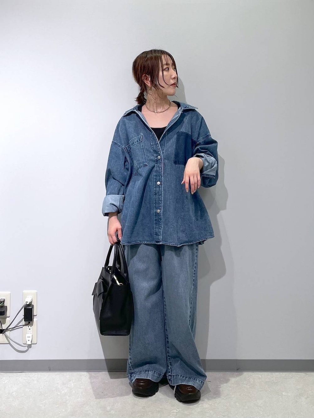 ブルー系のデニムパンツ、ブラック系のハンドバッグ、ブラウン系のローファーを着用したレディースの冬コーディネートの2枚目の写真