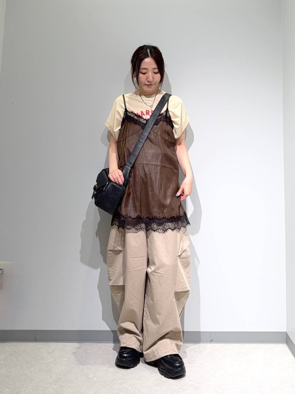 ベージュ系のTシャツ/カットソー、ブラウン系のキャミソール、ブラック系のショルダーバッグを着用したレディースの夏コーディネートの2枚目の写真