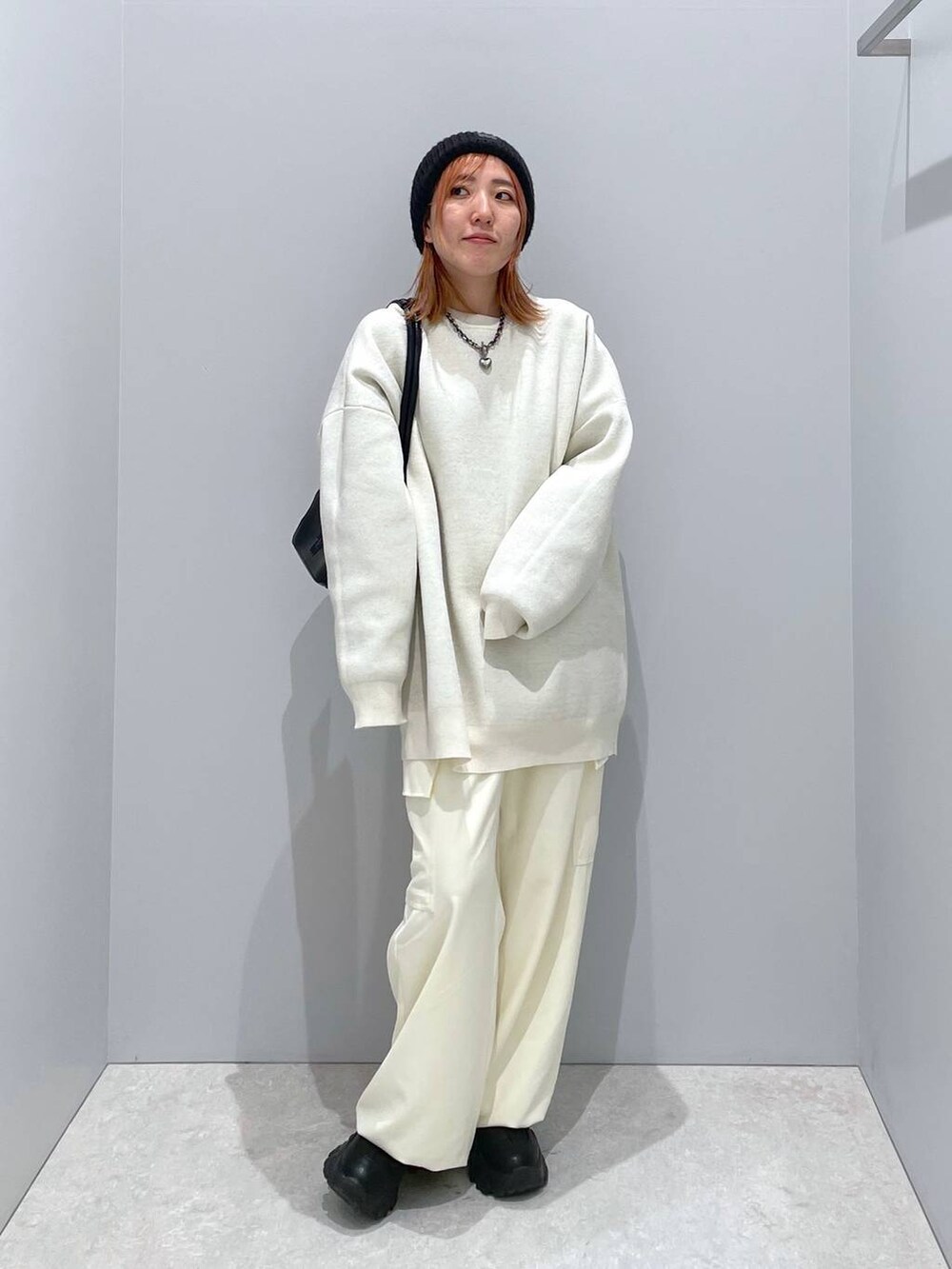 ブラック系のショルダーバッグ、ホワイト系のニット/セーター、ホワイト系のスラックスを着用したレディースの冬コーディネートの3枚目の写真